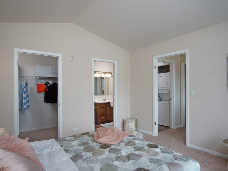 This image shows an expansive view of the bedroom area, starring the passage rooms to the walk-in closet, bathroom area, and the washer and dryer room.