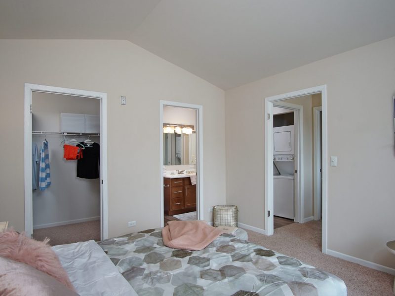 This image exhibits the bedroom area showcasing the light tone color wall, elegant fabrics, and an overlooking view of TGM McDowell Place outside that was ideal for a comfy pleasure.