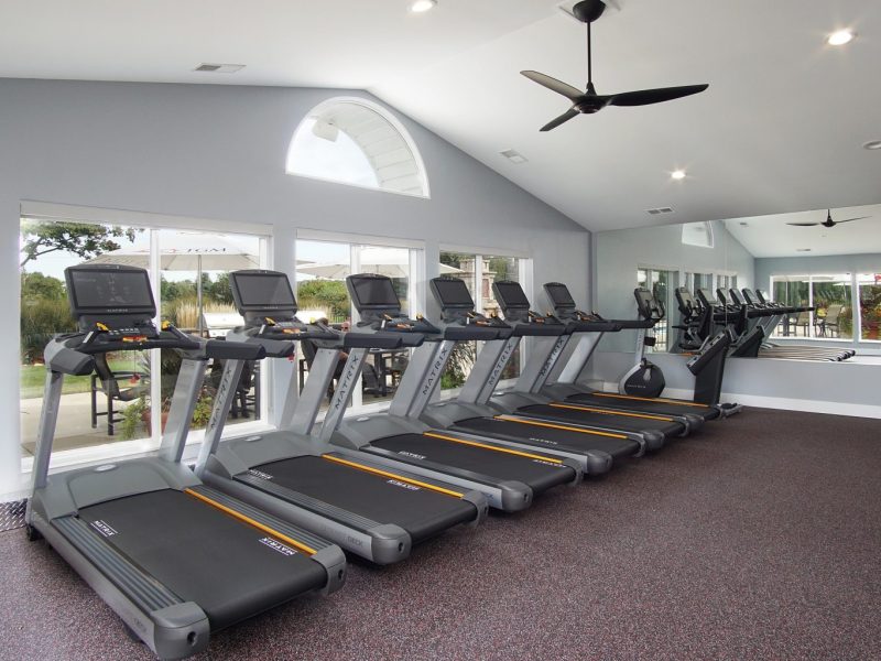 This image shows an expansive view of the 24-hour State-of-the-art fitness gym featuring different equipment that is essential for community amenities. The Athletic Club is offering a spacious area that was accessible to everyone and bringing up the different weights of dumbbells that were good for strength and chest workouts.