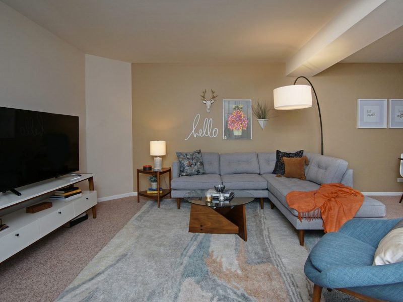 This image shows the living room area starring elegant sofas and Accent chairs. The living room area is also offering a flat-screen TV and quick access to the dining room.