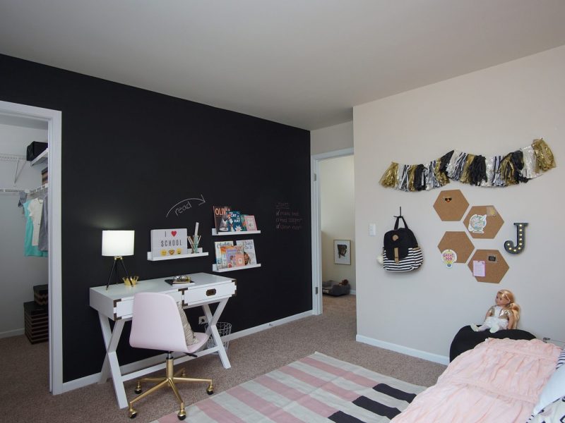 This image shows the working station inside the bedroom area featuring its pure black wall paint and fancy wall decors with a walk-in closet beside.